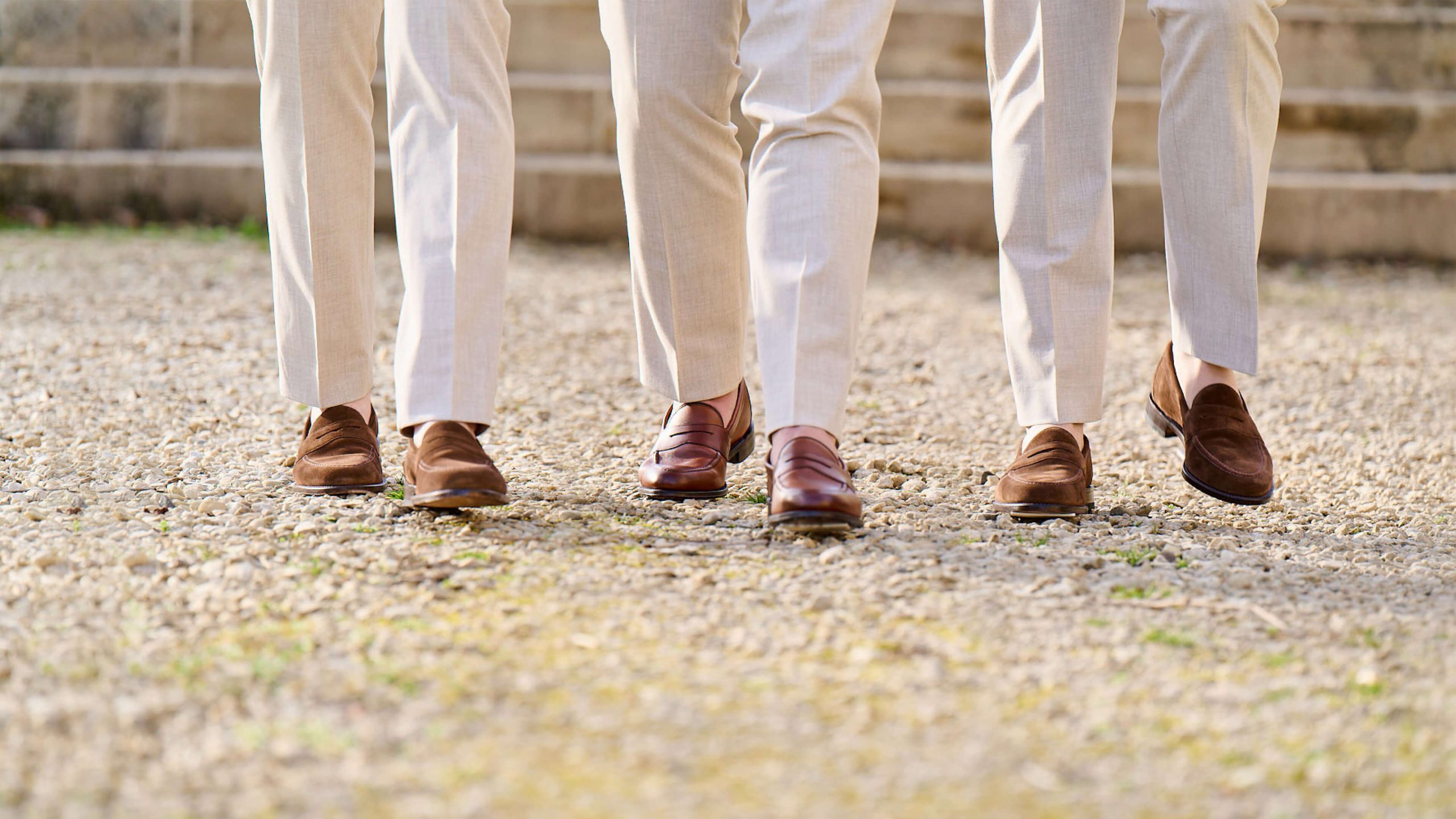 Collection brown loafers worn my gentleman in beige trousers on a gravel driveway